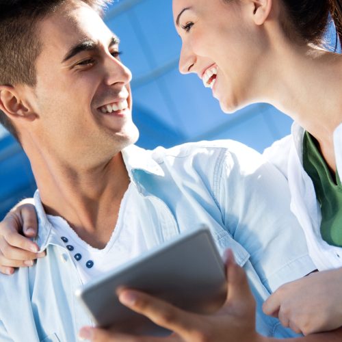 Outdoor portrait of one young couple using a digital tablet