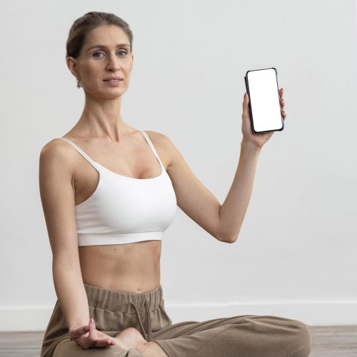 mujer-en-casa-haciendo-yoga-y-sosteniendo-smartphone