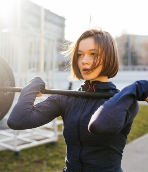 Strong woman exercising with barbell. Cute girl preparing for weightlifting workout. Sports, fitness concept.