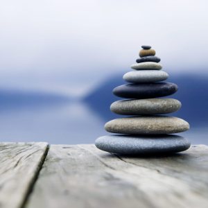 Zen balancing pebbles next to a misty lake.