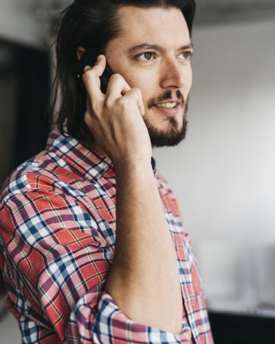 retrato-de-un-hombre-joven-inteligente-en-camisa-cuadros-hablando-por-telefono-celular